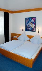 a bedroom with a large bed with white sheets at Hotel Gülser Weinstube in Koblenz