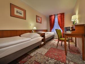 プラハにあるEA Hotel Jeleni Dvur Prague Castleのベッド2台とデスクが備わるホテルルームです。