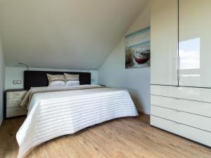 a white bedroom with a bed and a dresser at LieblingsPlatz im Sonnengarten in Kellenhusen