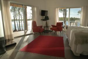 1 dormitorio con 1 cama y algunas sillas y ventanas en Al Natural Posada, en Nueva Palmira