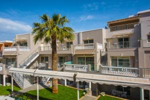 an exterior view of a building with a palm tree at Sarpidon Apartments in Malia