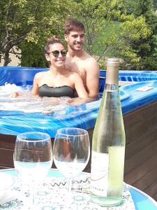 Ein Mann und eine Frau im Schwimmbad mit einer Flasche Wein. in der Unterkunft Horti del Baio in Apiro