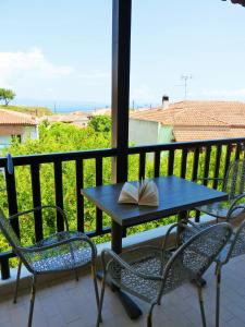 a table and chairs on a balcony with a book on it at Yannis Apartments in Afitos