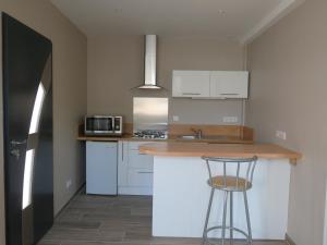 a kitchen with white cabinets and a counter with a stool at Le gîte de Ballage in Chemillé-sur-Dême
