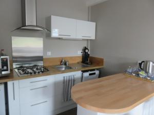 a kitchen with white cabinets and a wooden counter top at Le gîte de Ballage in Chemillé-sur-Dême +1 photo