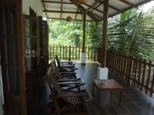 a row of wooden chairs and tables on a porch at Baby Elephant Green House in Udawalawe