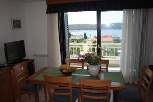 ein Esszimmer mit einem Tisch und einem großen Fenster in der Unterkunft Apartments Villa Olga in Rab