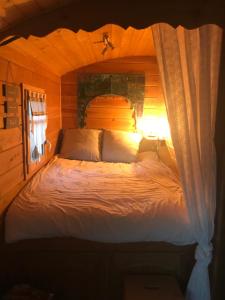 1 dormitorio con 1 cama en una habitación de madera en La roulotte au fond du pré, en Coltines