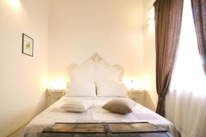 1 dormitorio con 1 cama blanca, 2 mesas y ventana en La Piccola Atene, en Pietrasanta