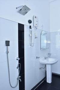 a white bathroom with a shower and a sink at Baby Elephant Green House in Udawalawe