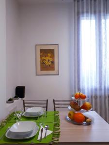 uma mesa de jantar com placemats e pratos verdes e frutas em Residenza Gavioli Via Angelelli - Parco Navile em Castel Maggiore