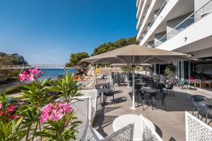 an outdoor patio with tables and chairs and flowers at ARTIEM Audax - Adults Only in Cala Galdana