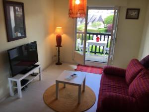 een woonkamer met een bank, een tv en een tafel bij Le Studio 102 in Villers-sur-Mer
