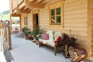 a porch of a wooden cabin with a bench and flowers at Schlosswirt Chalets & Apartments in Großkirchheim