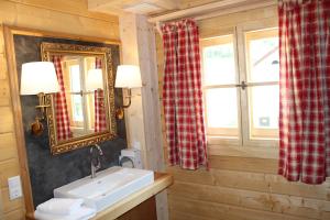 a bathroom with a sink and a mirror and a window at Schlosswirt Chalets & Apartments in Großkirchheim