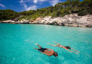 two people laying in the water in the ocean at ARTIEM Audax - Adults Only in Cala Galdana