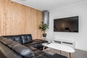 a living room with a leather couch and a tv at Tallbackens Gård & Vandrarhem in Svärtinge