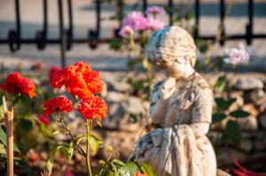 a statue of a girl in a garden with red flowers at Hotel dell'Ulivo in Cassano delle Murge