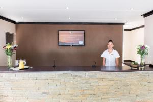 a woman standing behind a counter in a room at Arebbusch Travel Lodge in Windhoek