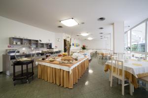 une cuisine avec des tables et des chaises ainsi qu'une cafétéria dans l'établissement Hotel Plaza, à Rimini