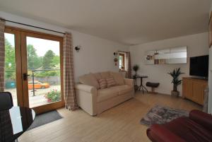 sala de estar con sofá y puerta corredera de cristal en The Coach House Annexe, en Llangollen