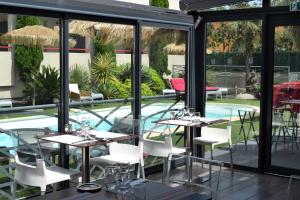 ペルピニャンにあるLogis Hôtel La Fauceilleのテーブルと椅子のあるレストラン、スイミングプールを提供しています。