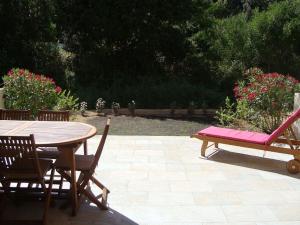 een houten tafel en stoelen met een tafel en een bank bij PIETROSELLA Plage du RUPIONE in Pietrosella