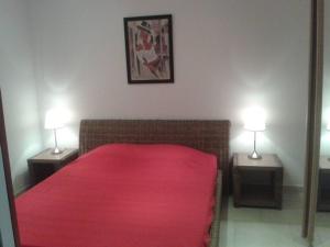 een slaapkamer met een bed met een rode deken en 2 lampen bij PIETROSELLA Plage du RUPIONE in Pietrosella