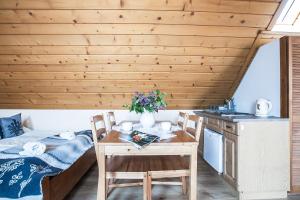 a room with a table and a bed and a kitchen at Willa Arkady in Zakopane