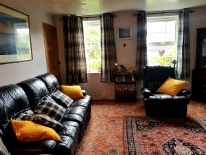 a living room with a leather couch and two chairs at Argyllholidaycottage Loch Awe in Eredine