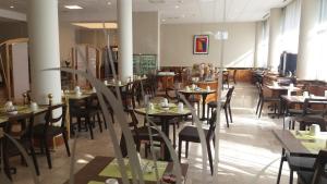 a restaurant with tables and chairs in a room at Logis Lyon Est Porte de l'Ain in Saint-Maurice-de-Beynost