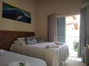 a bedroom with two beds and a large window at Mares de Camburizinho in Camburi
