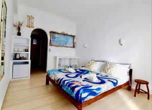 a bedroom with a bed with a blue and white comforter at Thomas Art Hotel in Pelekas