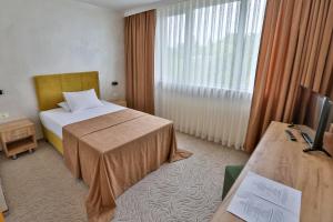 a hotel room with a bed and a television at Terra Europe Brontes Hotel in Targovishte
