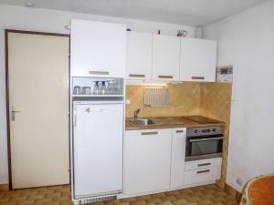 a white kitchen with a refrigerator and a sink at Studio La Lagune by Interhome in Le Grau-du-Roi