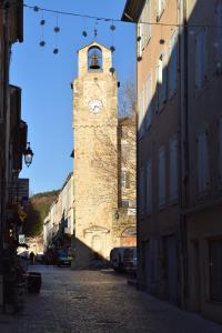 una torre del reloj en medio de una calle en Séjour provençal en Dieulefit