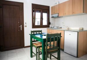 a kitchen with a green table and two chairs at Yannis Apartments in Afitos