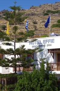a hotel with flags in front of a mountain at Effie Hotel in Skala