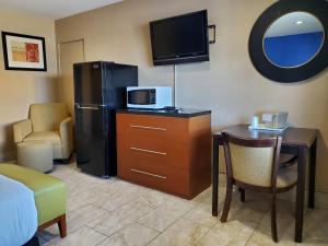 a room with a desk with a microwave and a refrigerator at PineCrest Inn & Suites in Flagstaff