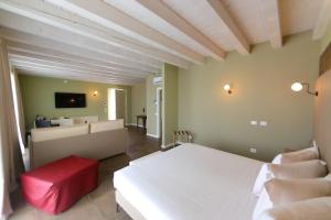 Le Greghe Suites في لازيسي: غرفة نوم بسرير ابيض وغرفة معيشة