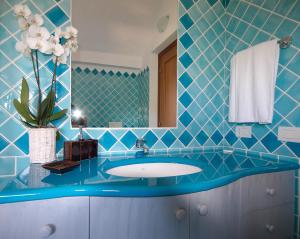 a blue tiled bathroom with a sink and a mirror at Hotel Nibaru in Porto Cervo