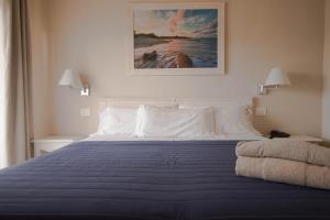a bedroom with a large bed with a blue blanket at Hotel Nibaru in Porto Cervo