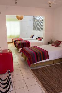 a hotel room with two beds and a red suitcase at Hotel Avenida en Arica in Arica