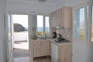 a kitchen with wooden cabinets and a view of the ocean at Palaiokastro view in Karpathos Town