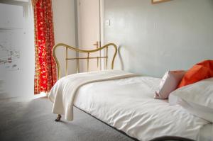 a bedroom with a white bed with a red curtain at Room Only Corbies Rest in Inverness