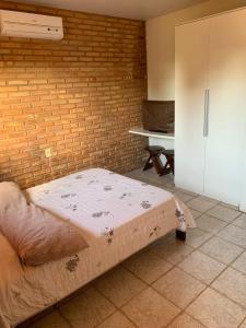 um quarto com uma cama e uma parede de tijolos em Casa na Praia - Parkrio Sauaçuhy - Maceió - AL em Maceió