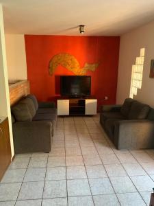 a living room with two couches and a flat screen tv at Casa na Praia - Parkrio Sauaçuhy - Maceió - AL in Maceió