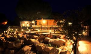 a house with a stone wall in front of it at night at LAS CABAÑAS DEL LAGO in Córdoba