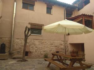 El Corralón - Casa Rural en Sigüenza في سيغوينزا: طاولة نزهة مع مظلة أمام المبنى