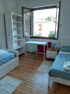 a bedroom with two beds and a desk and a window at Alloggio il Giglio in Schio